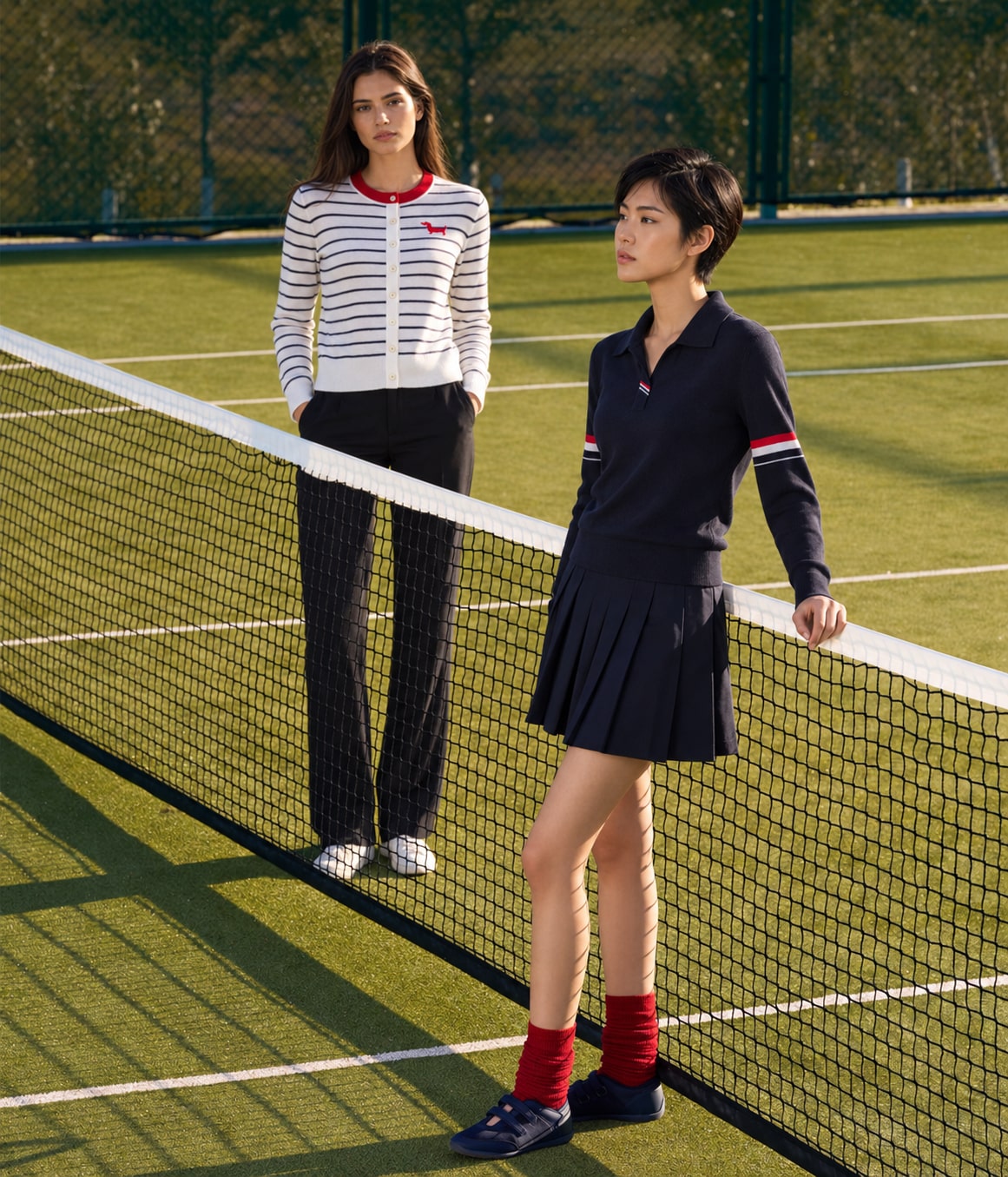 Two models wearing striped cardigan TH861025 and navy knit polo TH861051 on a tennis court